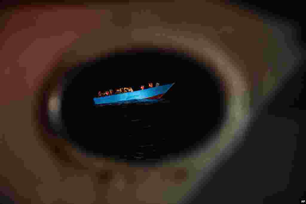 Dozens of migrants from Egypt, Morocco, Somalia and Sierra Leone, including women and minors, wait to be assisted by a team of aid workers of the Spanish NGO Open Arms, after spending more than 20 hours at sea when fleeing Libya on board a precarious wooden boat in the Central Mediterranean sea, Sept. 8, 2020.