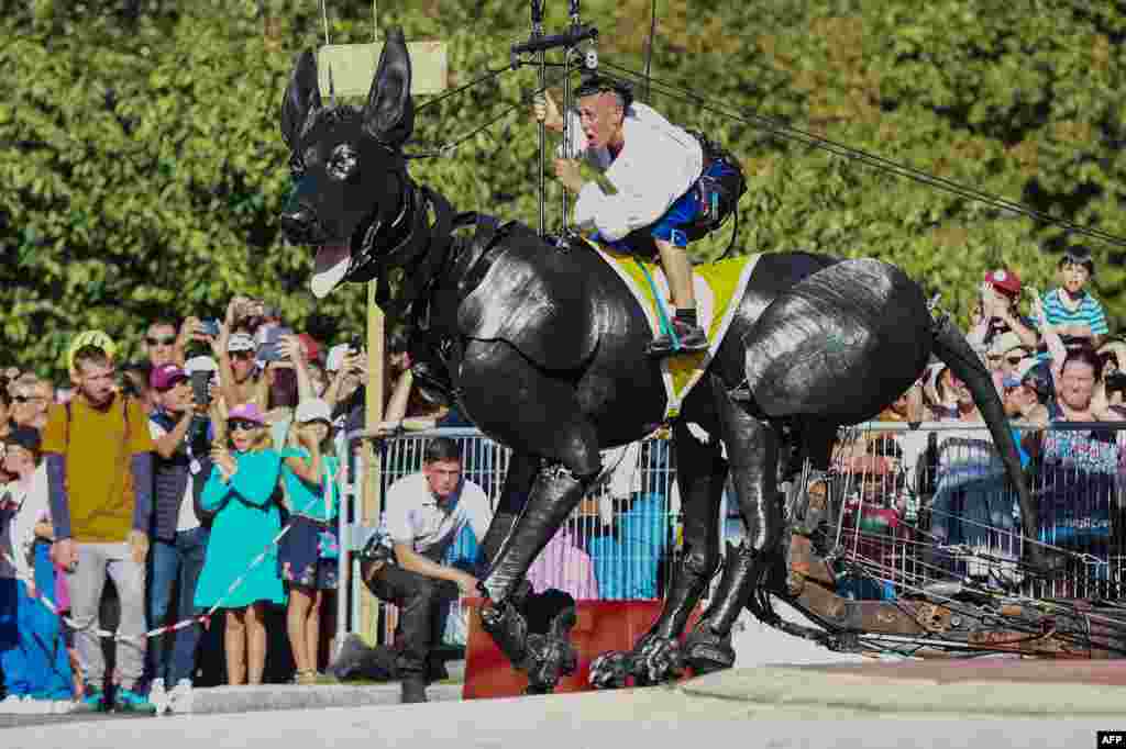 Members of the French street theatre company "Royal de Luxe" perform on Xolo, a giant dog puppet, during the show "Le Bull Machin de Mr Bourgogne" in Nantes, France, Sept. 24, 2023.