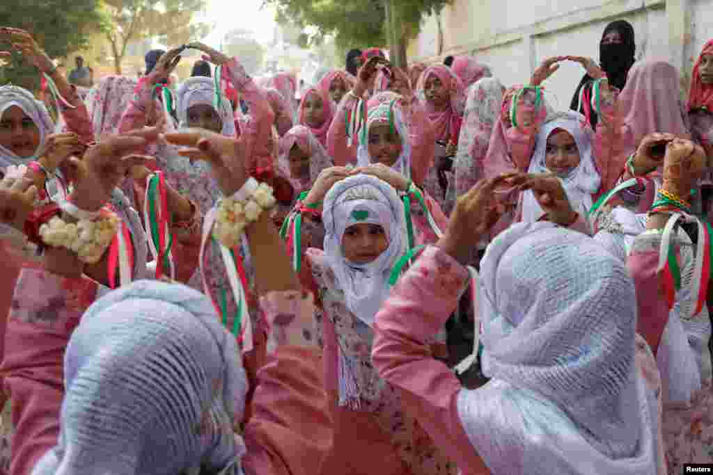 Girls wearing hijabs gesture during a religious chant at a celebration to mark the birth anniversary of Prophet Mohammad, in Karachi, Pakistan.