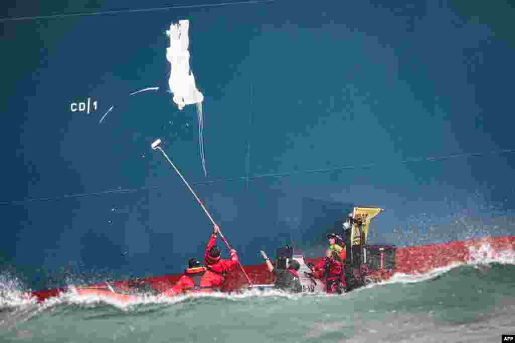 Greenpeace France activists paint the words 'Gas Kills' on the side of the TotalEnergies Cape Ann LNG terminal, anchored off the northern French port city of Le Havre, in the English Channel.