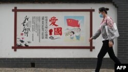一名女子走過北京街頭的一面中國政府宣傳社會主義核心價值的宣傳牆。（2021年6月9日）