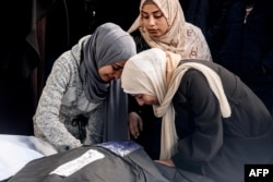 Palestinke oplakuju rođaka člana porodice ubijenog u noćnim izraelskim bombardovanjima juga Pojasa Gaze, stojeći nad njegovim telom u bolnici u Rafi, 8. februara 2024.