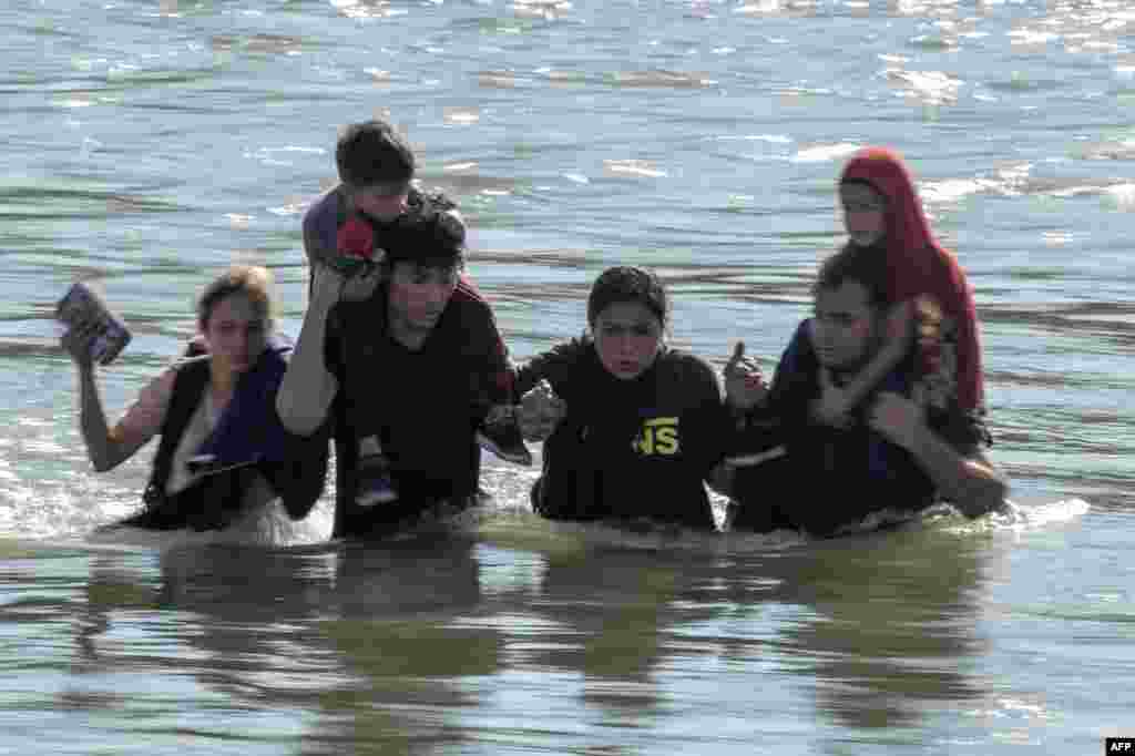 A family holds on as they try to navigate swift currents in the Rio Grand river as they cross the US-Mexico border to Eagle Pass, Texas, Sept. 23, 2023.