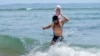 Jerome Quirion, de Sherbrooke, Quebec, Canadá, regresa a la orilla después de aventurarse en el frío océano Atlántico con su hija de 18 meses, Amelie, mientras estaba de vacaciones, en Old Orchard Beach, Maine, el martes 18 de junio de 2024.