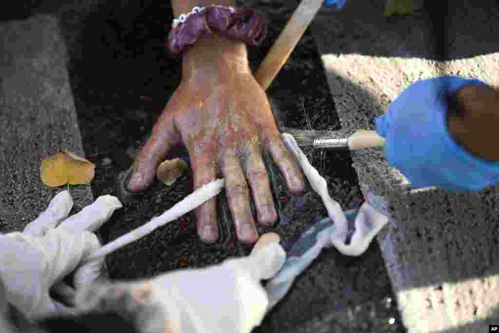 Police officers remove the glued hand of a climate activist from a road during a climate protest in Berlin, Germany.
