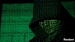 FILE - Binary code is projected onto a hooded man in this illustration photo taken on May 13, 2017. U.S. officials say that terror groups like IS and al-Qaida have reinvented themselves in recent years, posing new threats. (TPX Images via Reuters) 