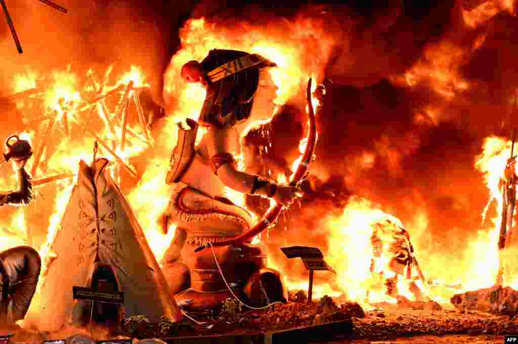 Ninots (cardboard figurines) in a 'falla' (a huge ornate cardboard sculpture made to eventually be burnt) are seen burning on the night of the Fallas Festival in Valencia, Spain, March 19, 2023.