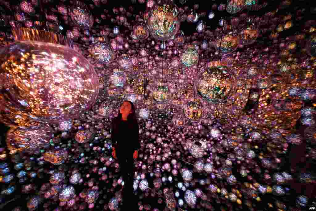 A staff member stands at the interactive artwork "Bubble Universe" during a media preview of the teamLab Borderless: MORI Building Digital Art Museum at Azabudai Hills in Tokyo, Japan.