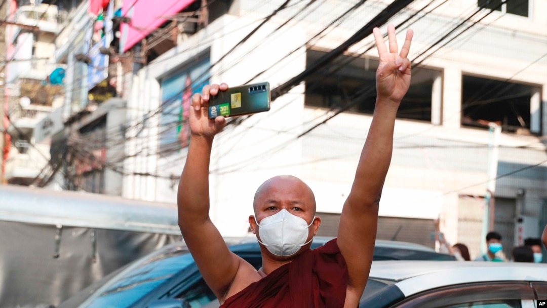 FILE - A Buddhist monk carrying a smart phone flashes a three-fingered salute in a gesture of solidarity as protesters march in Yangon, Myanmar, Feb. 7, 2021. Myanmar’s military government has launched an effort to block free communication on the internet.