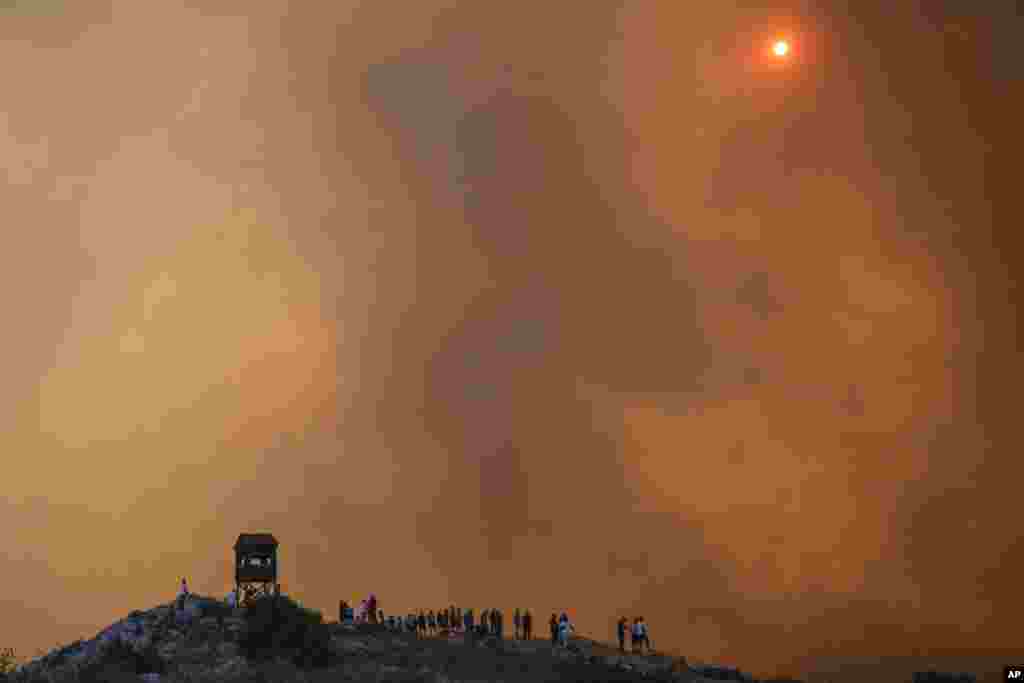 People watch a wildfire in Mandra west of Athens, Greece.