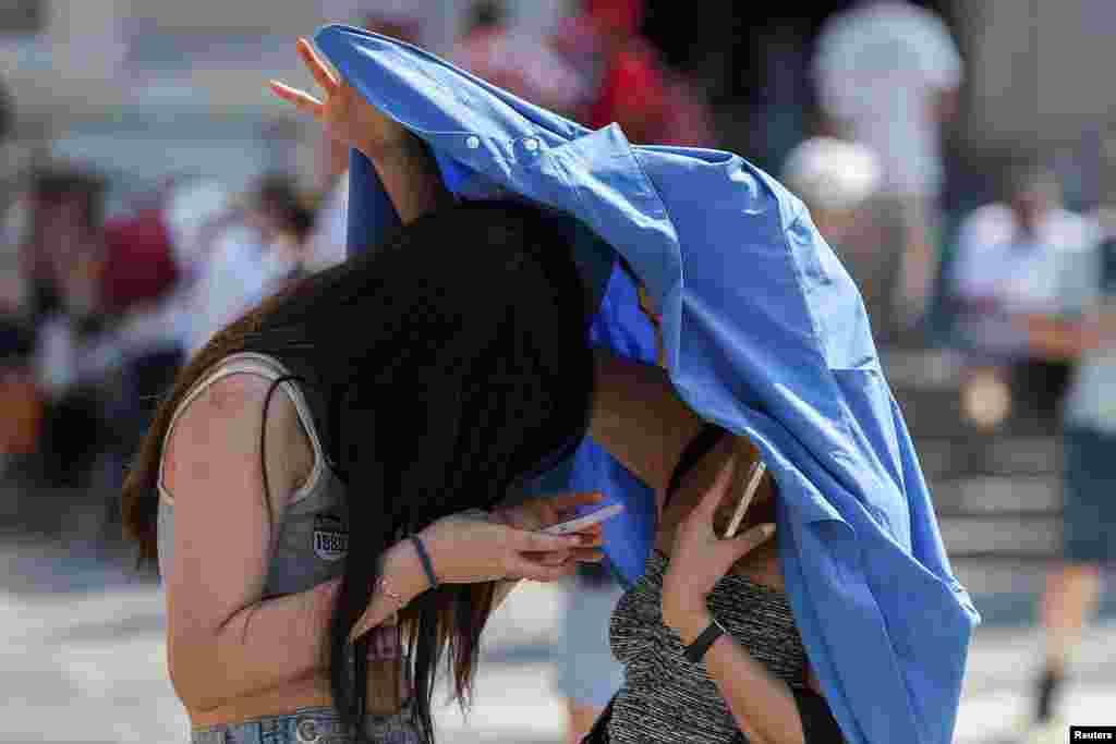 People use a piece of clothing to hide from the sun, during a heat wave in Milan, Italy.