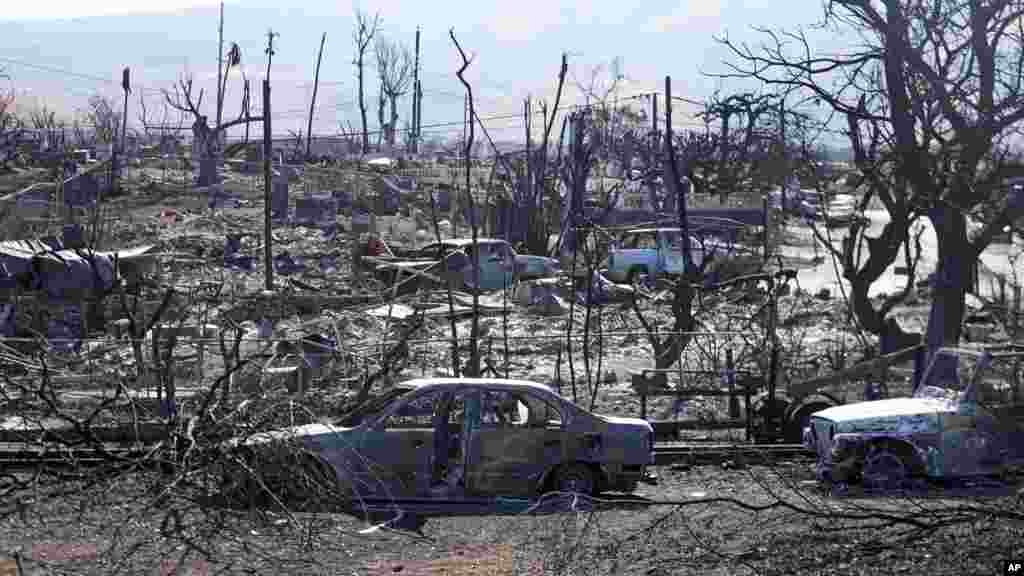 Destroyed homes and cars are seen, Aug. 13, 2023, in Lahaina, Hawaii. Hawaii officials urge tourists to avoid traveling to Maui as many hotels prepare to house evacuees and first responders on the island where a wildfire demolished a historic town and killed dozens. 