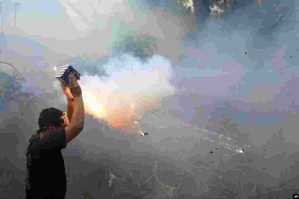 A protester launches fireworks at riot police during a demonstration, in solidarity with the Palestinian people in Gaza, near the U.S. embassy in Aukar, a northern suburb of Beirut, Lebanon.