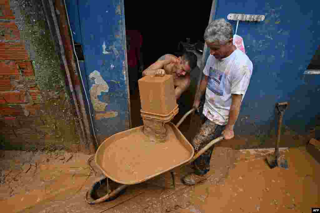 People remove mud from a flooded house after torrential rain caused flooding and landslides at the Juquehy district in Sao Sebastiao, Sao Paulo state, Brazil.