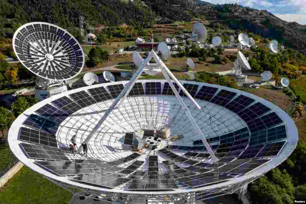 Employees of Swiss electricity producer and supplier CKW, part of Axpo, install solar panels in a satellite dish at the Leuk Teleport and Data Center in Leuk, Switzerland, Oct. 18, 2023.
