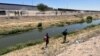 En Ciudad Juárez, México, una mujer camina con su hijo por el borde del Río Bravo buscando entregarse a las autoridades el 11 de mayo de 2023.