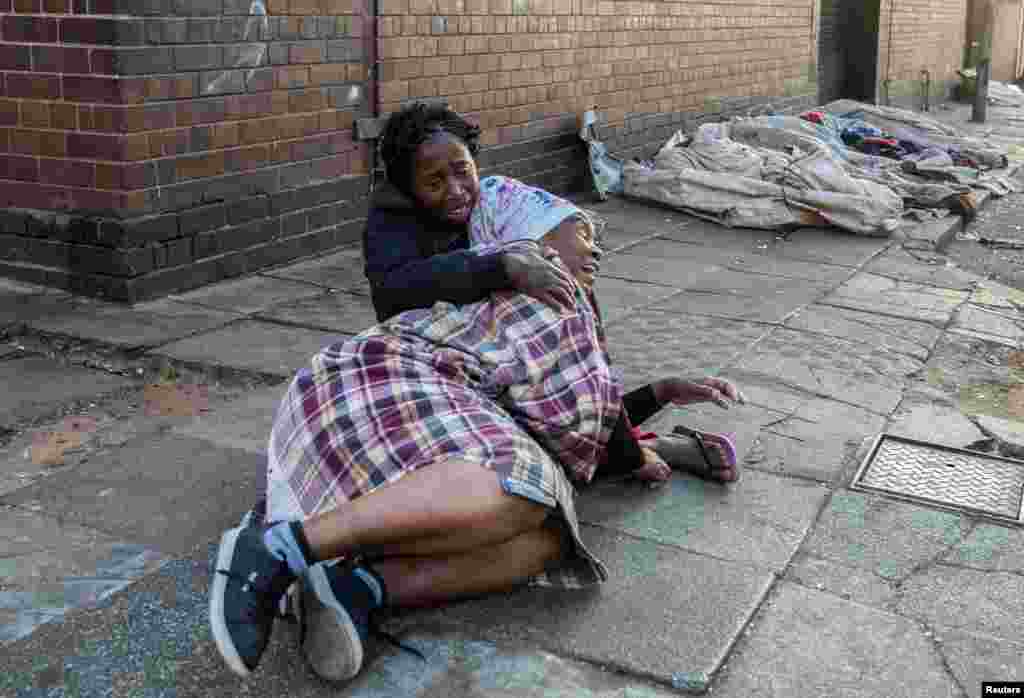 Women react after a deadly blaze in the early hours of the morning, in Johannesburg, South Africa. More than 70 people were killed overnight when a fire raged through a run-down, five-story apartment block.