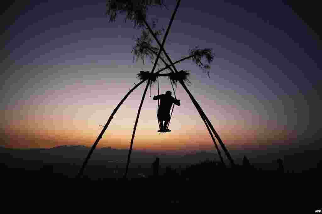A boy sways on a swing traditionally called the 'Dashain Ping' on the occasion of the Nepali Hindu festival 'Dashain' near the Changu Narayan temple in Bhaktapur on the outskirts of Kathmandu.
