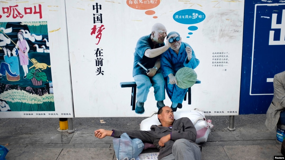 資料照：一名農民工在北京火車站的一個中國夢的政府宣傳牌下打盹。