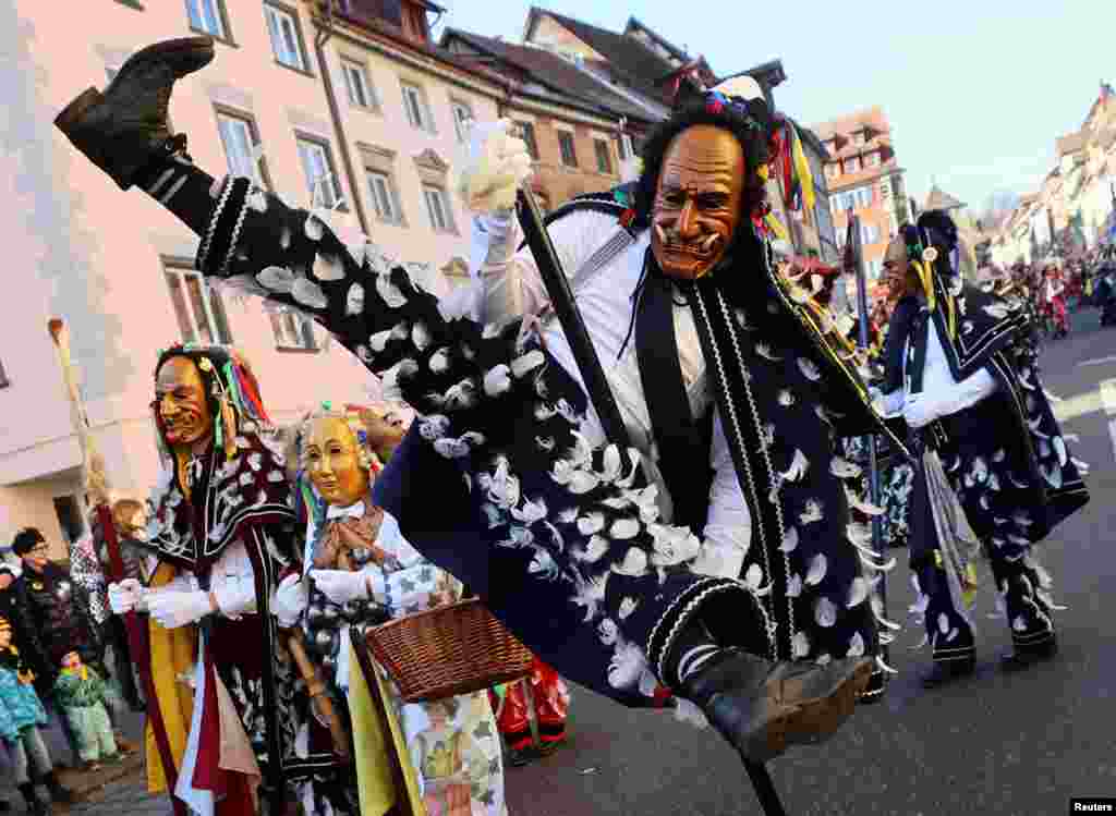 A carnival reveler jumps during the traditional folklore procession "Narrensprung" ("Fools Jump") as part of the Swabian-Alemannic Rose Monday celebrations in the Black Forest town of Rottweil, Germany.