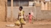 FILE - A child carries bags with bread as he walks in a street in Khartoum, Sudan, on June 20, 2023. 