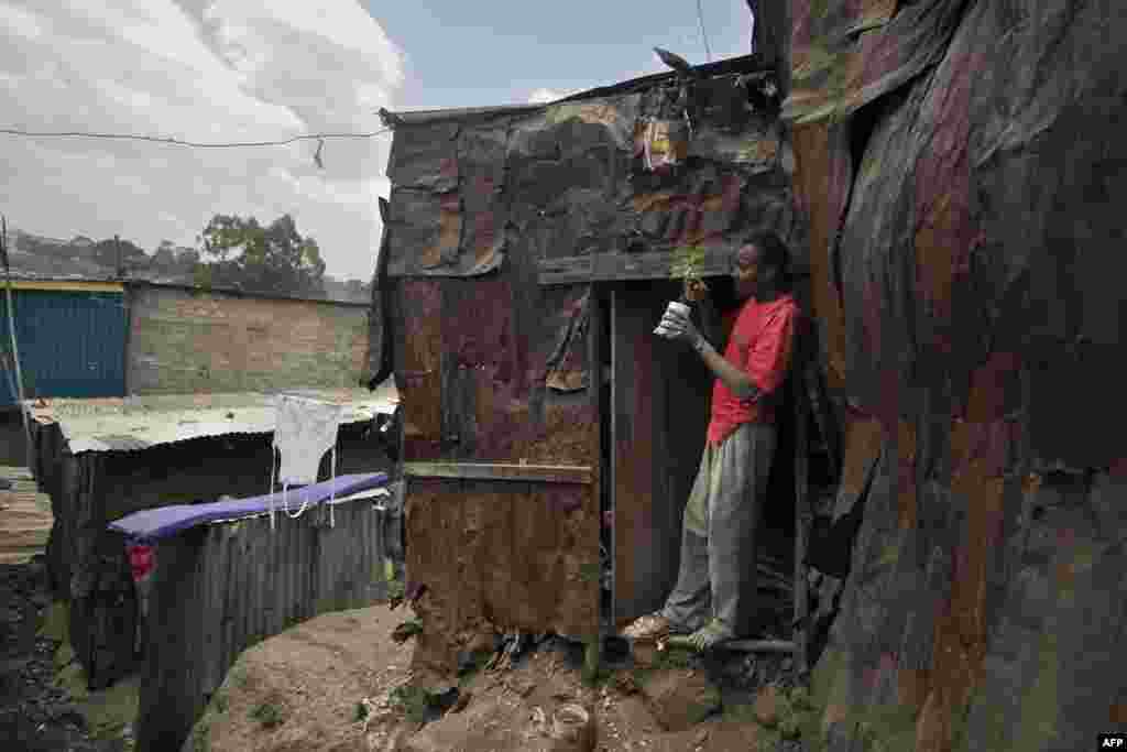 An artisanal carpenter checks on his avocado tree seedling during a break from work at his roadside workshop in the informal settlement of Mathare slum in Nairobi.