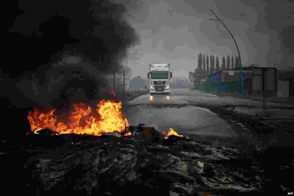 A truck drives towards a fire during a blockade as part of the movement against the government's proposed pensions reform on the Radicatel Terminal of the harbor in Port Jerome sur Seine, near Rouen, France.