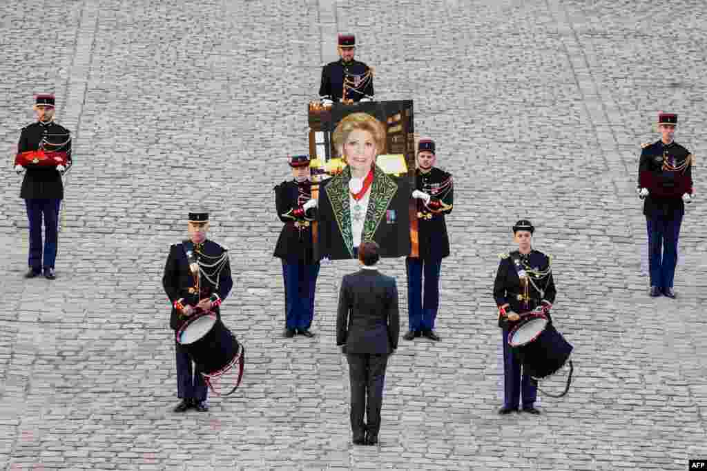 French President Emmanuel Macron (C) stands as Republican Guards carry a portrait of late French historian and perpetual secretary of the Academie Francaise (French Academy) Helene Carrere d'Encausse during a national homage in her tribute at the Hotel des Invalides in Paris.