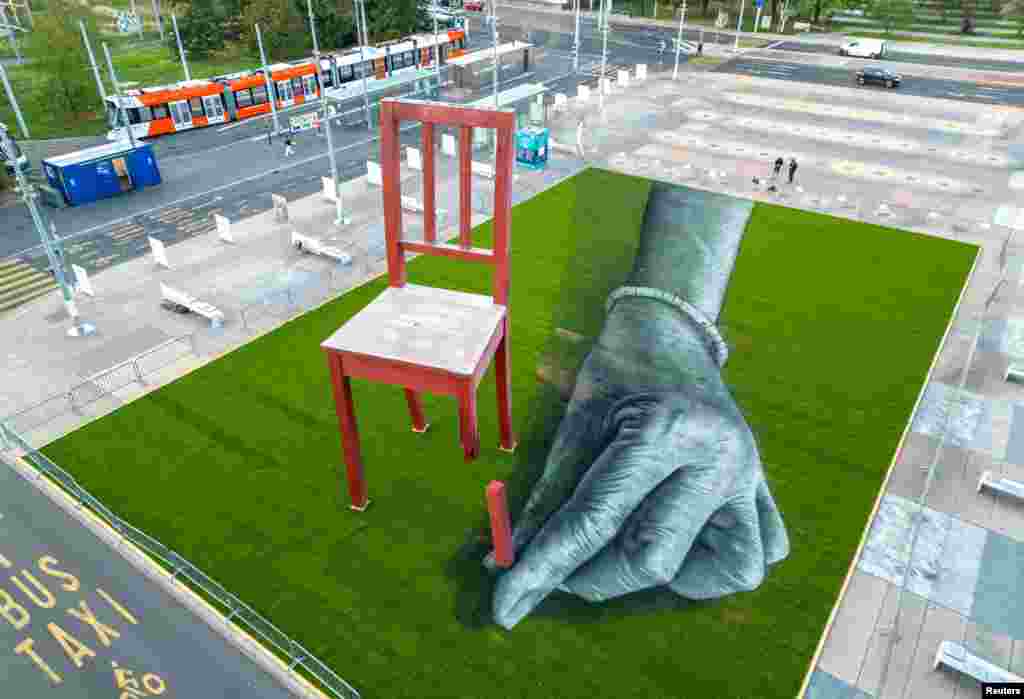 A land art painting called "ALL OF US!" made by Swiss French artist SAYPE is seen together with Broken Chair on the Place des Nations in front of the United Nations in Geneva, Switzerland, Sept. 11, 2023, to draw attention to the plight of civilians in armed conflicts.