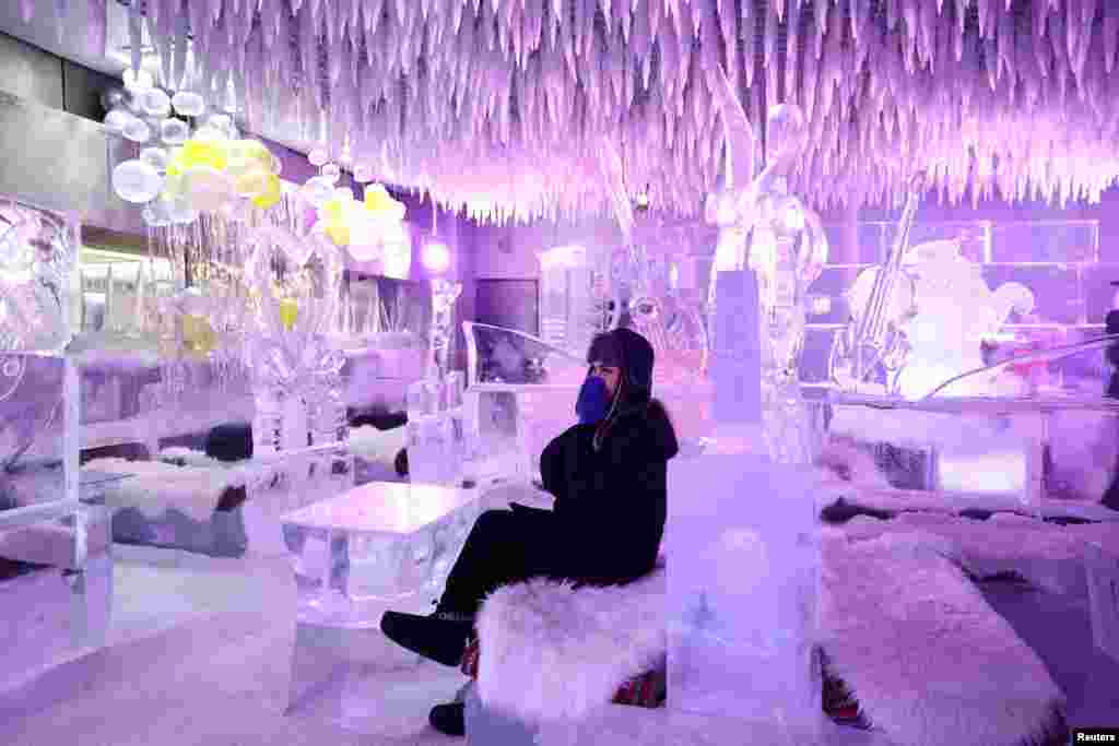 A guest sits on ice sculptor Mark Ranasinghe’s creations in freezing temperatures at Chillout Ice Lounge in Dubai, United Arab Emirates, Aug. 28, 2023.