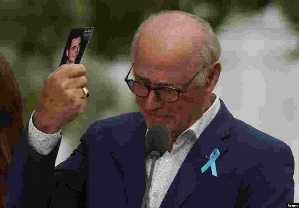 A father holds his son's picture as he attends a ceremony marking the 21st anniversary of the September 11, 2001 attacks on the World Trade Center at the 9/11 Memorial and Museum in the Manhattan borough of New York City.