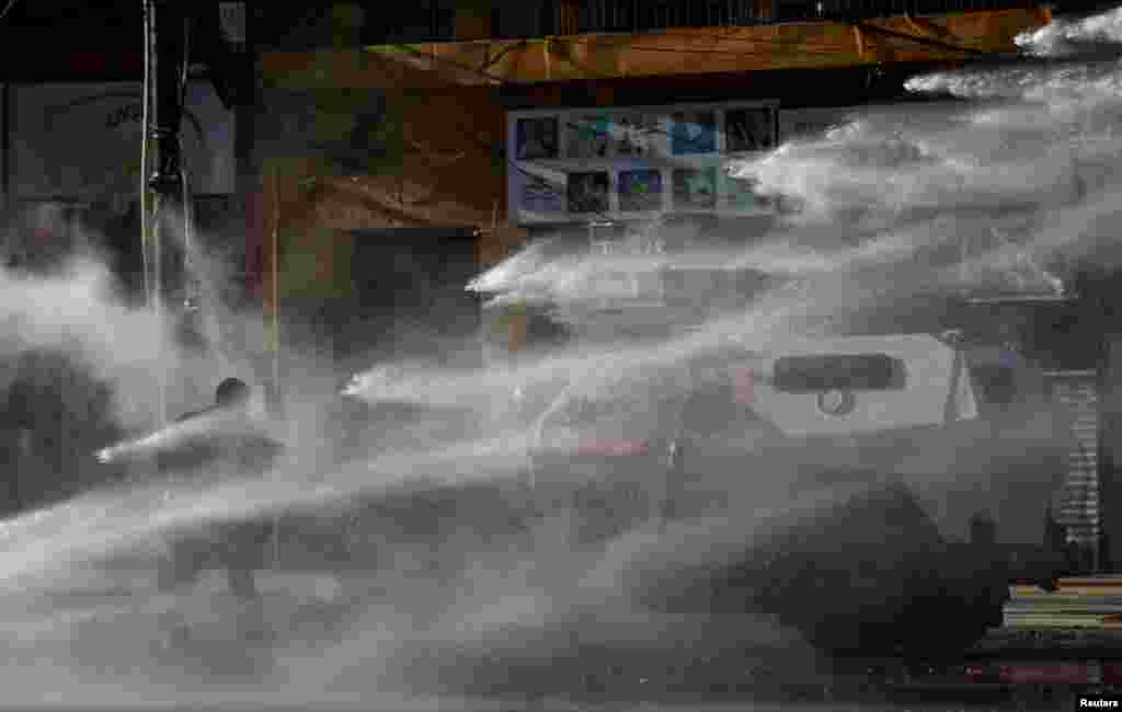 A demonstrator is hit by a jet of water from a riot police vehicle during a rally in Valparaiso, Chile, Oct. 18, 2023, on the fourth anniversary of the protests and riots that rocked the country in 2019.