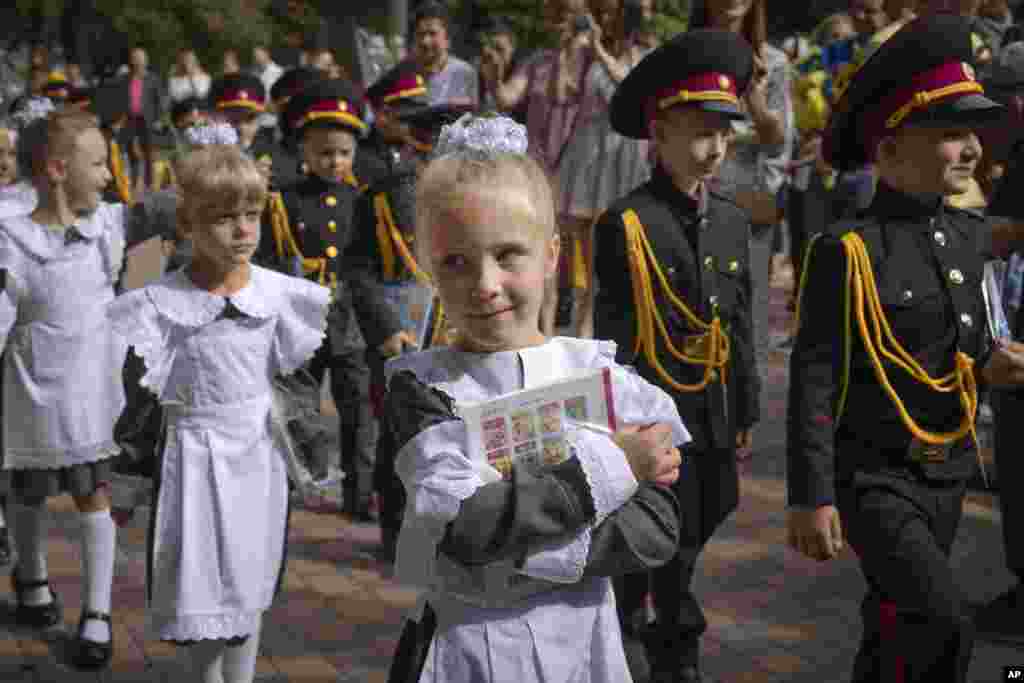A schoolgirl holds a primer during a ceremony on the first day of school at a cadet lyceum in Kyiv, Ukraine.