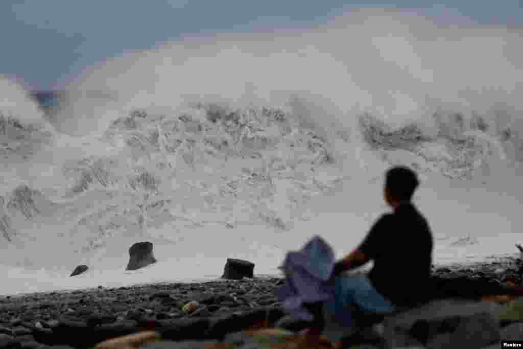 A woman looks at at waves as Typhoon Koinu approaches, in Taitung, Taiwan.