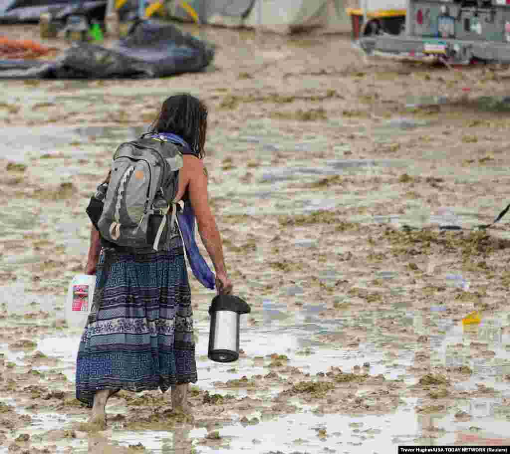 A Burning Man participant makes her way through the mud in Black Rock City, in the Nevada desert, after a rainstorm turned the site into mud, Sept. 2, 2023.