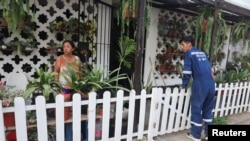 Un trabajador del Ministerio de Salud habla con un residente de un asentamiento antes de rociar insecticida para prevenir el dengue en Lima, Perú, 7 de marzo de 2024.