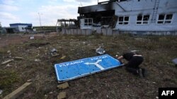 Fotografija snimljena 16. avgusta 2024, tokom medijske turneje koju je organizovala Ukrajina, prikazuje čoveka kako ispituje oštećeni putokaz sa strelicama za Ukrajinu i Rusiju, na uništenom graničnom prelazu u blizini grada Sudža, koji kontroliše Ukrajina, u Kurskoj oblasti.