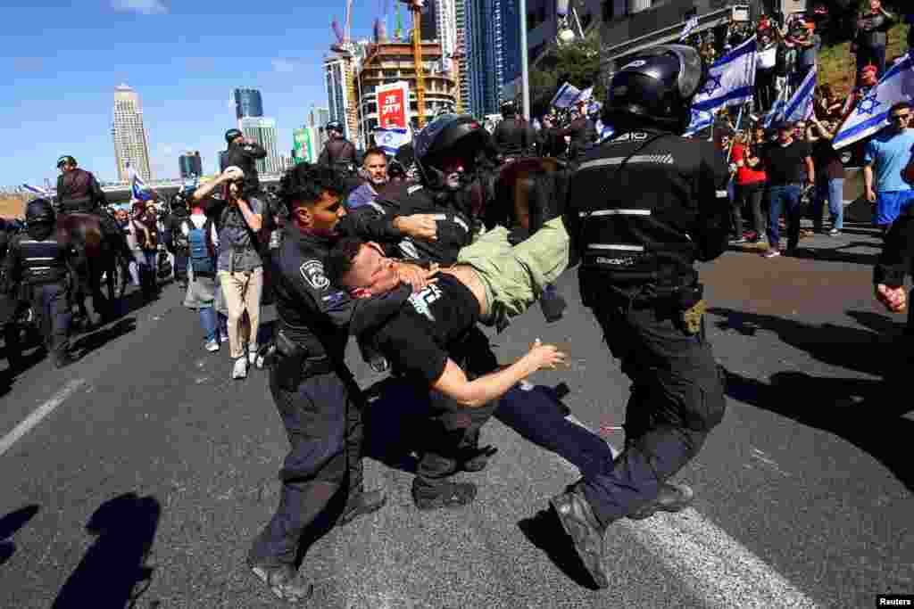 Israeli police officers detain a demonstrator during "Day of Resistance", as Prime Minister Benjamin Netanyahu's nationalist coalition government presses on with its contentious judicial overhaul, in Tel Aviv.