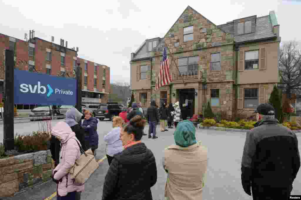 Customers wait in line outside a branch of the Silicon Valley Bank in Wellesley, Massachusetts, March 13, 2023.