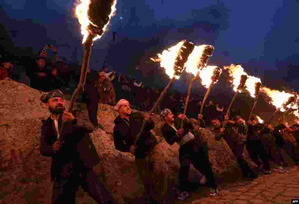 Iraqi Kurds holding torches walk up a mountain during a procession to celebrate their Nowruz New Year festival in Akre, the country's northern autonomous Kurdish region, March 20, 2023.