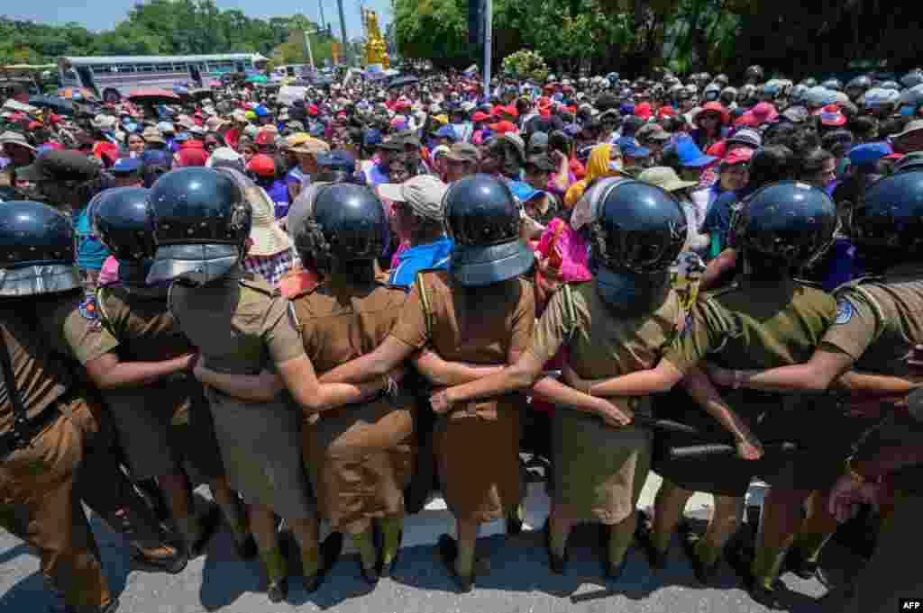 Policewoman stand guard as anti-government demonstrators take part in a protest organized by the "Women for Rights" group on the occasion of International Women's Day near the parliament building in Colombo, Sri Lanka.
