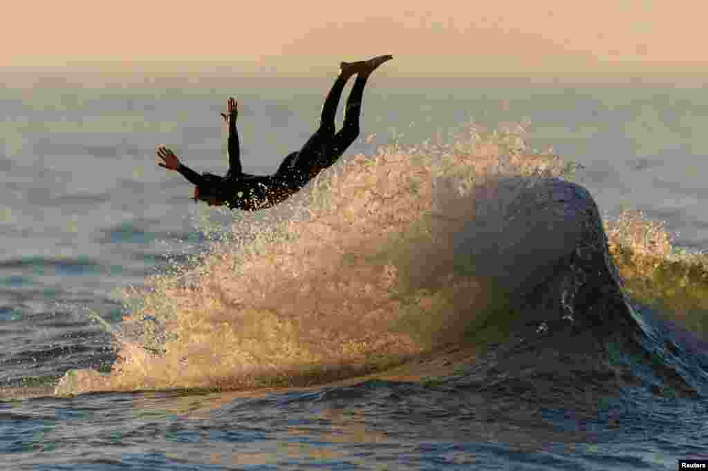 A surfer dives off his board while surfing at sunset in Encinitas, California, Aug. 28, 2023.
