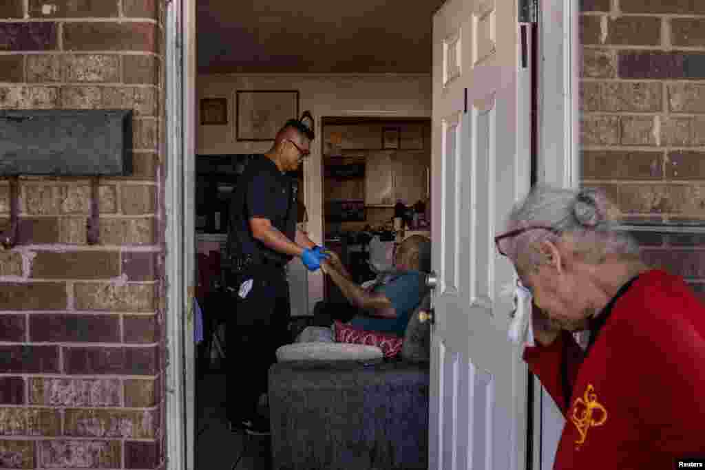 McNeese, 67, reacts as Eric Bailon, a paramedic with the Galveston County Health District, assesses her partner Jordan, 85, after medics say he overheated and fell in his kitchen during a heat wave in Galveston, Texas, Aug. 27, 2023.
