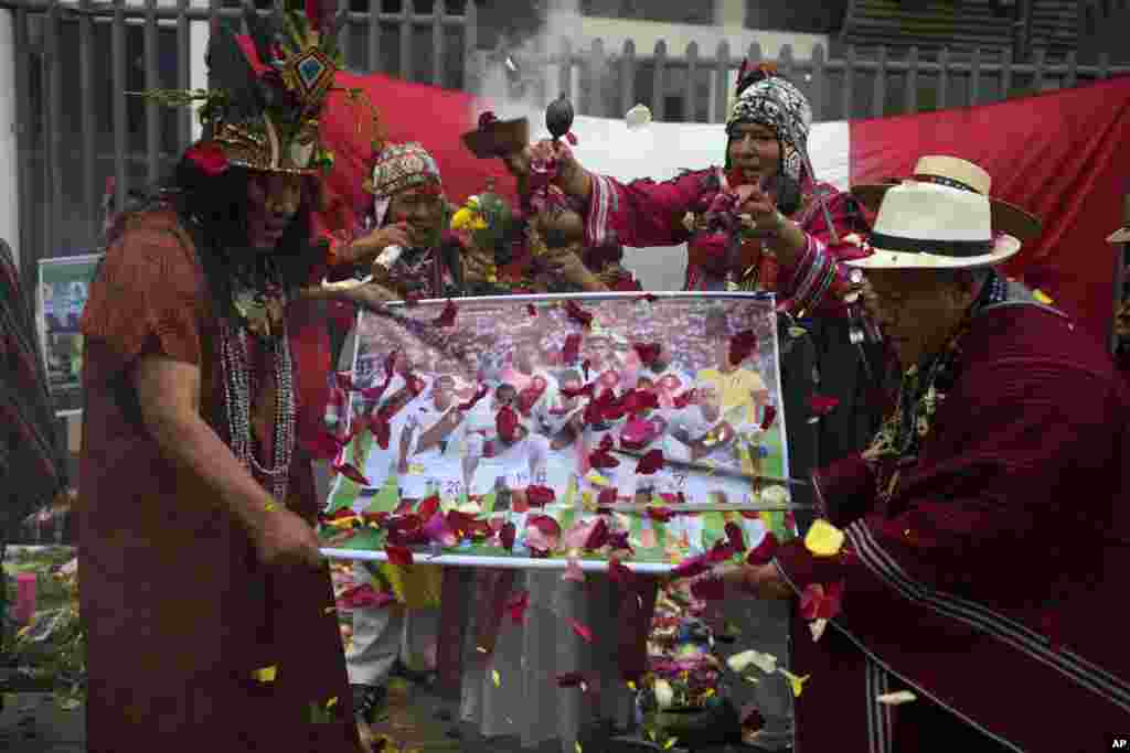 Peruvian shamans hold a poster of Peru's national soccer team while performing a good luck ritual outside the National Stadium in Lima.