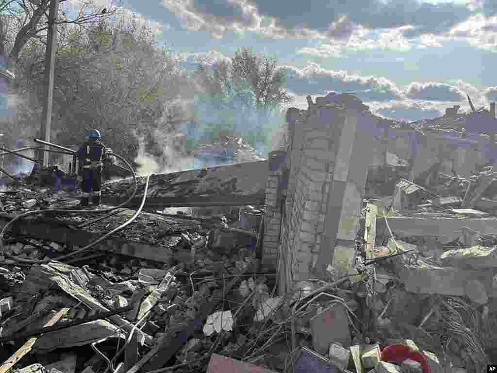 In this photo provided by the Ukrainian Presidential Press Office, firefighters extinguish a fire after the deadly Russian rocket attack that killed more than 40 people in the village of Hroza near Kharkiv, Ukraine.