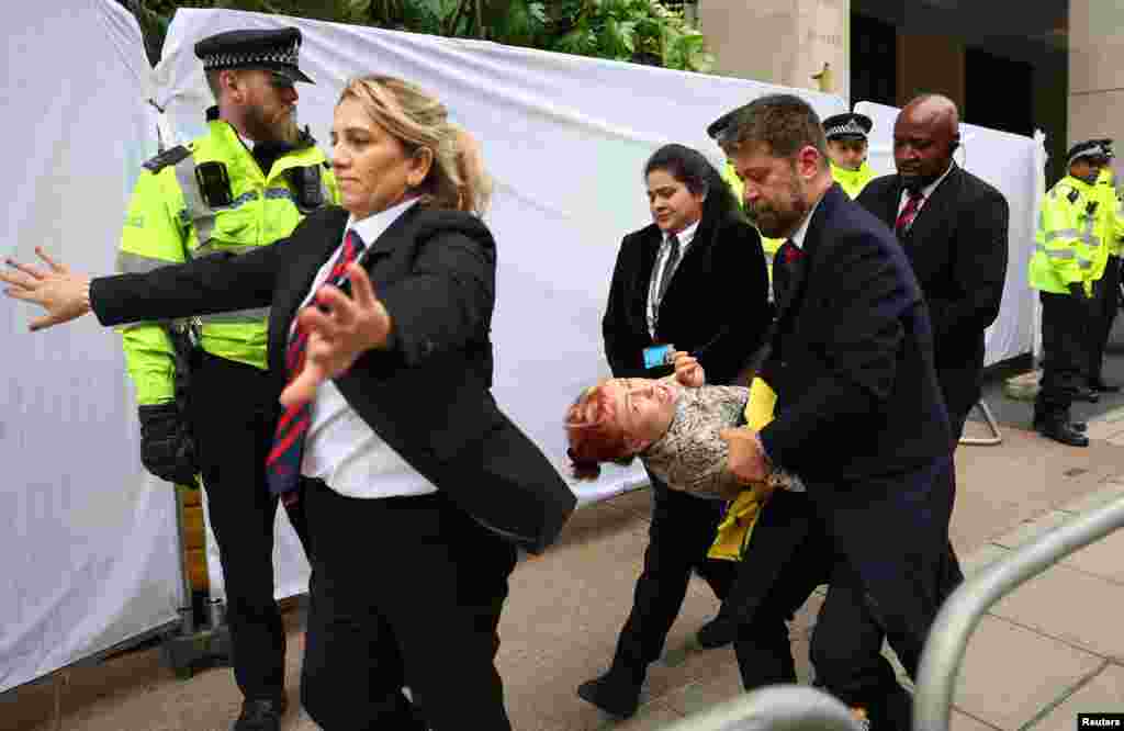 Police officers and security staff remove a demonstrator from the venue of the Energy Intelligence Forum, as Oily Money Out protests take place outside, in London.