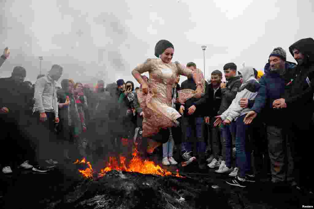 A woman jumps over a bonfire during an event to celebrate Nowruz, which marks the arrival of spring, in Istanbul, Turkey, March 19, 2023.