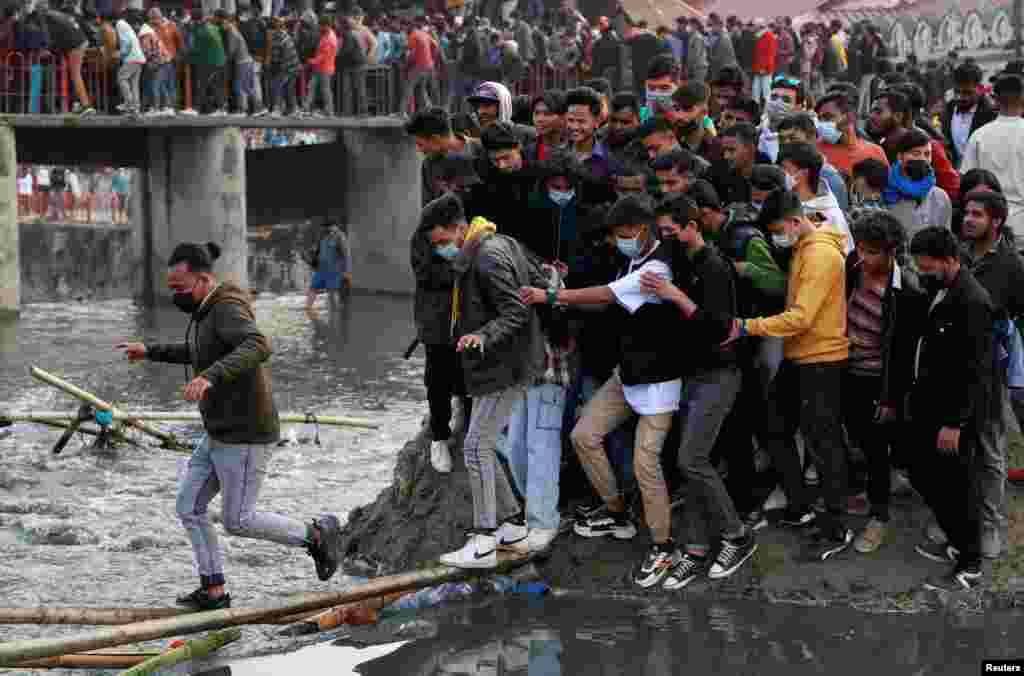 People try to cross the Bagmati River to avoid the crowded bridge at the premises of Pashupatinath Temple during the Shivaratri festival in Kathmandu, Nepal, Feb. 18, 2023.
