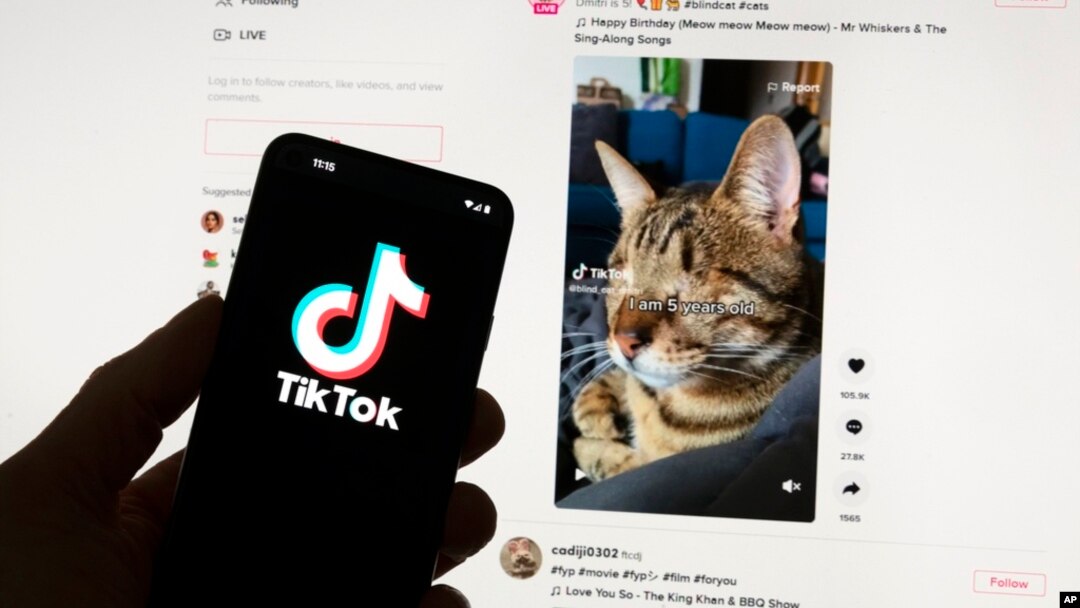 Logo TikToka se vidi na mobilnom telefonu ispred kompjuterskog ekrana koji prikazuje kućni ekran TikToka, 18. mart, 2023. (Foto: AP/Michael Dwyer)