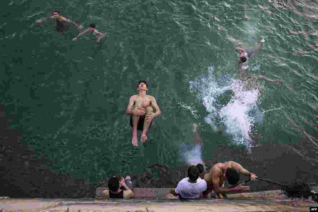 A young man jumps into the Mediterranean sea off the coast of Khan Yunis in the southern Gaza Strip during a heat wave.